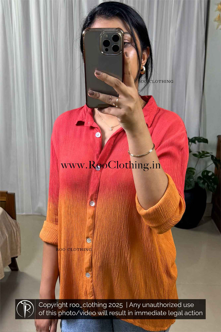 Person wearing a red and orange gradient shirt taking a mirror selfie.