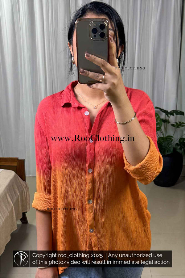 Person wearing a red and orange shirt taking a mirror selfie with a blurred background.